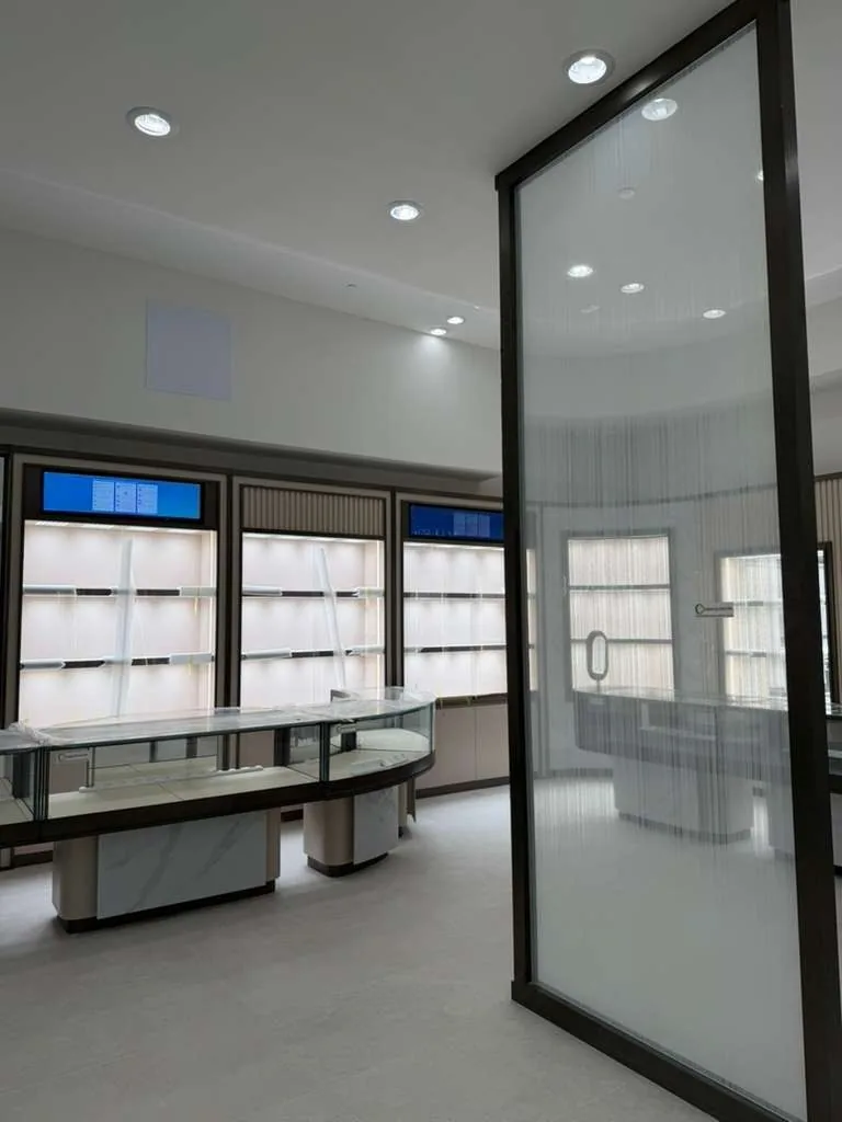 Lit wall display bays above a curved case, seen past the consultation room glass